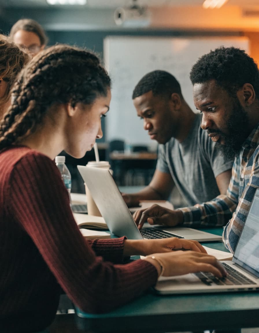 Adult students working together on laptops in a classroom